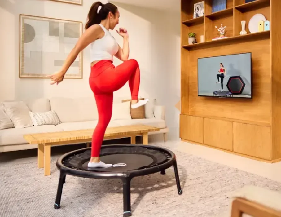 Woman doing high knees on a BERG rebounder in front of a television