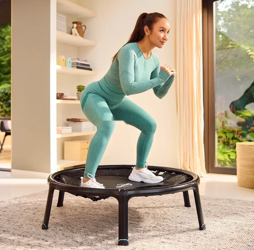 Woman doing a squat on a BERG rebounder in a living room